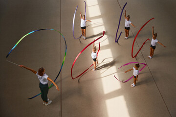 Aerial view. Female sports coach training gymnastics athletes at sports gym, indoors. Concept of...