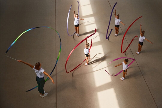 Aerial view. Female sports coach training gymnastics athletes at sports gym, indoors. Concept of sport, studying, art, education