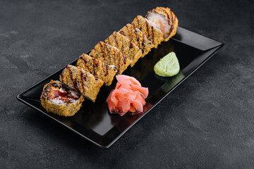 Served warm sushi with ginger and wasabi on a black stone plate
