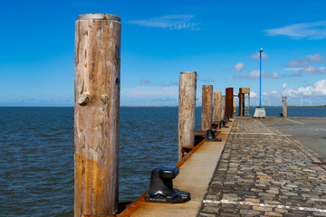 Wooden pillar or mooring post along a quay in a harbor - obrazy, fototapety, plakaty