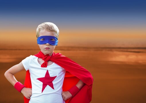 Composite image of caucasian boy wearing a superhero costume against sunset sky