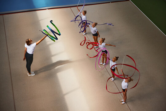Aerial view. Female sports coach training gymnastics athletes at sports gym, indoors. Concept of sport, studying, art, education