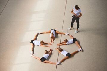 Aerial view. Female sports coach training gymnastics athletes at sports gym, indoors. Concept of...