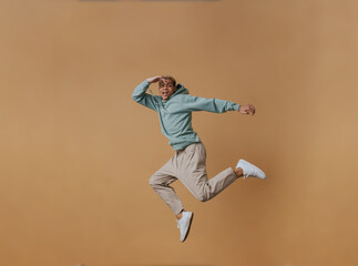 Fototapeta na wymiar Blonde young man wearing hoodie making fun and jumping