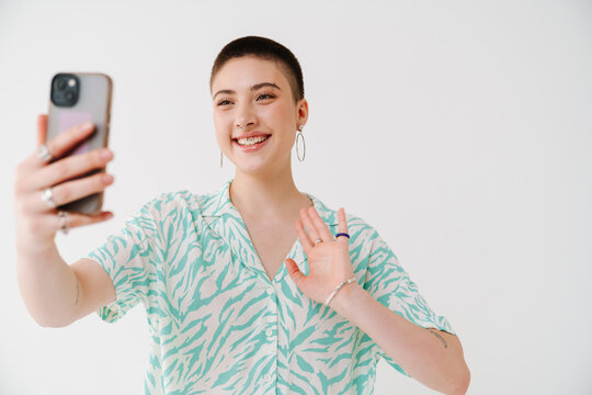 Young woman gesturing and taking selfie photo on cellphone