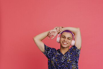 Young handsome smiling stylish boy in headphones with raised hands