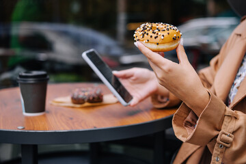 woman eating donuts and looking at phone