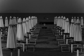 Sun loungers and umbrellas on the private beach. Black and white photo.