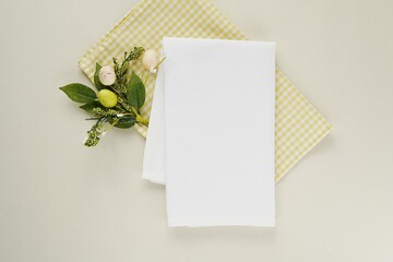 White plain kitchen towel mockup on yellow checkered tablecloth, folded cotton tea towel for Easter design presentation.