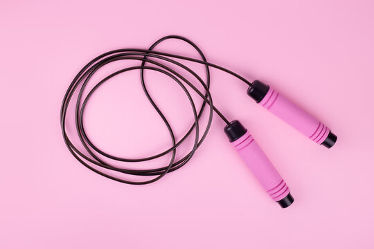 Fitness concept. Top view photo of pink skipping rope on isolated pastel pink background with copyspace.