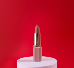 Nude, beige Lipstick on White Podium on red background. Design Template of Fashion Cosmetics Product for Ads, flyer, banner or Magazine Background.