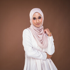 Portrait of a beautiful female model wearing hijab, a lifestyle apparel for Muslim women isolated on brown background. Idul Fitri and hijab fashion concept.