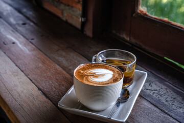 Hot coffee latte with latte art milk foam in cup mug ,hot tea on wood desk on top view. As breakfast In a coffee Vintage style shop at the cafe,during business work concept