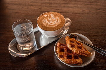 Homemade Belgian Waffles with honey and Hot coffee latte with latte art milk foam in a swan shape in cup mug  on wood desk on top view. As breakfast In a coffee shop at the cafe,during business work.