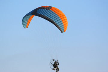 Paramotor pilot flying in a blue sky	