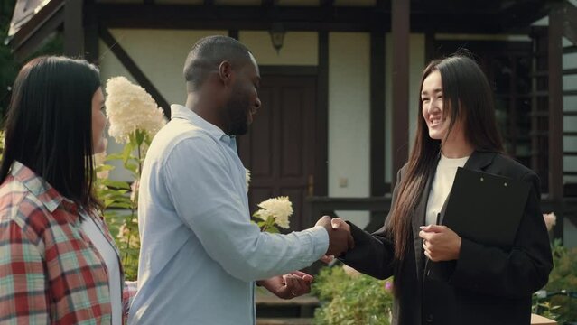 Asian female real estate agent sells house to African husband and Caucasian wife and hands over the keys.Multiracial Family,Mixed Race,Diverse People,Multiethnic Relations