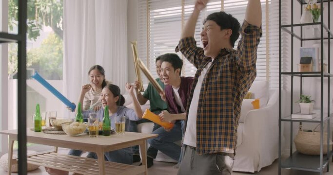 Group of young adult friend man and woman asia people sit at sofa couch joy chanting party fun game match world cup live TV at home eat snack bowl drink beer bottle glass jump mad happy win exult face