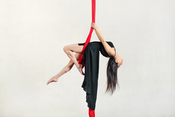 Flexible woman exercising on aerial silks - obrazy, fototapety, plakaty