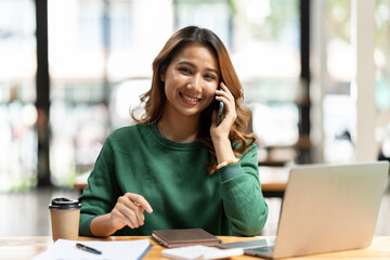 Asian businesswoman in formal suit in office happy and cheerful during using smartphone and working.