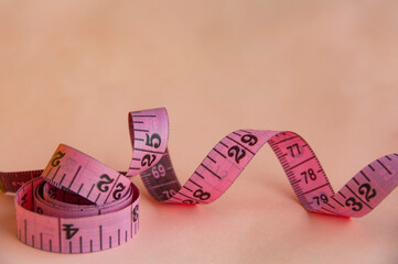Red measuring tapes on pink cover background with customizable space for text or ideas. Copy space...