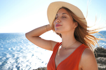 Portrait of young woman enjoying fresh air on face on her luxury vacation resort on beach. Summer...