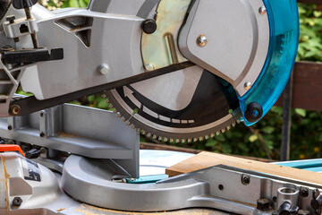 Close up of miter saw in the process of sawing off a wooden part.