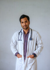 Portrait of a south asian handsome male doctor who is wearing a white apron and having a stethoscope in hand