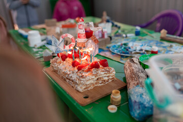 cake with candles and a lighthouse on a table with driftwood