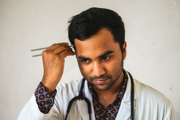 South asian doctor with a tuning fork in hand. Bangladeshi medical student with neurological diagnostic tool. - obrazy, fototapety, plakaty