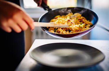 Woman cooking tasty scrambled eggs in frying pan 