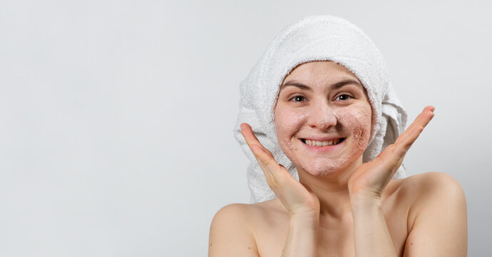 A young smiling woman with a natural mask or ubtan on her face and a white towel on her head, a place to text, copy space