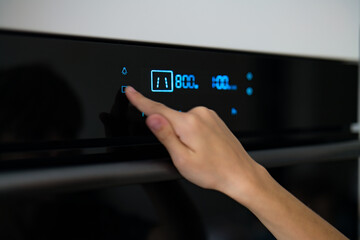 child's hand presses the buttons on the microwave. Closeup of black microwave control panel with cooking time.