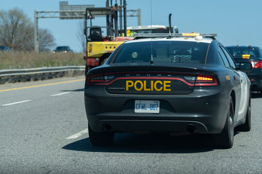 Close view of OPP Dodge Charger police cruiser interceptor following a car on the highway. Dangerous, careless driving, speeding, DUI, traffic violations concept.