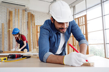 A male carpenter uses a pencil to write on a piece of wood. carpentry concept making wooden furniture house construction.