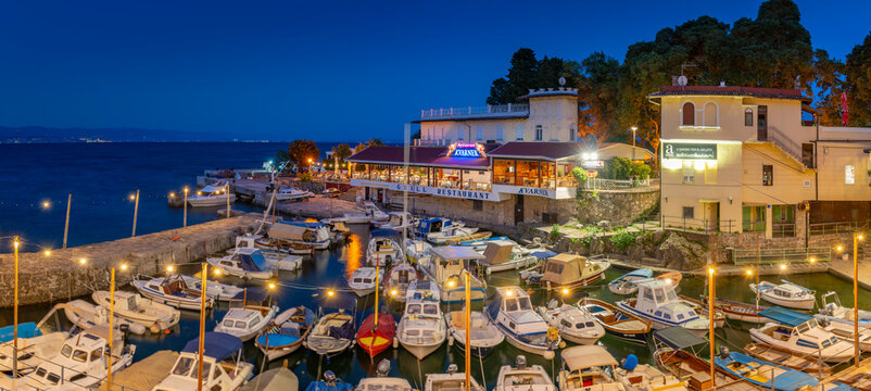 View of cafe and restaurant overlooking boats in harbour at dusk, Lovran village, Lovran, Kvarner Bay, Eastern Istria, Croatia
