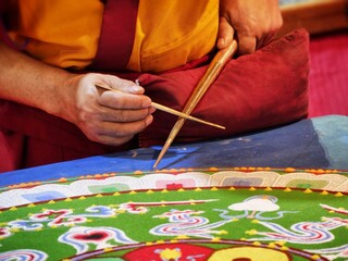 Buddhist monk create mandala with multicolor sands selective focus on hands Turin Italy March 24...