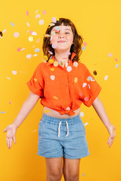 Cheerful girl standing under confetti
