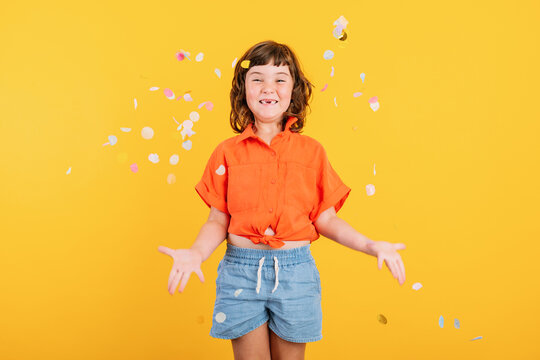 Cheerful girl standing under confetti