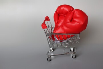 Boxing gloves inside shopping trolley with copy space. Fight inflation concept