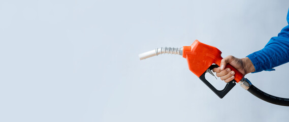 Person holding a gas nozzle on a white background, fuel consumption, petrol-fueled cars, fluctuating oil prices, using alternative fuels for driving. - obrazy, fototapety, plakaty