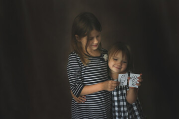 Fototapeta Funny Sisters Girls With Painted Toys On A Dark Background, Concept Childhood And Sublimation obraz