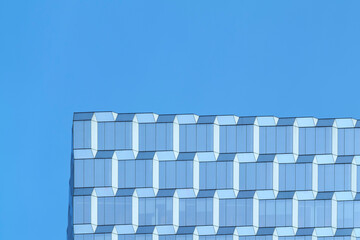 Reflection on the surface of a modern glass office building against blue sky background in...