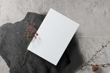 Clean minimal book 4x6 mockup on black stone with plant and stick