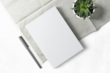 Clean minimal book 4x6 mockup on cloth with plant and pen