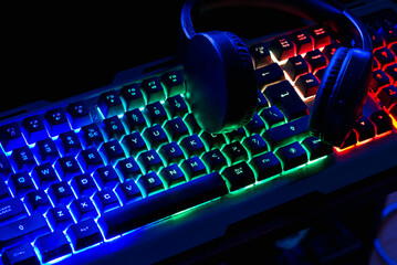 Pro gaming illuminated desk, headset, keyboard, computer neon lights. Cyber sport equipment laying...