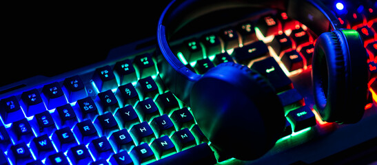 Pro gaming illuminated desk, headset, keyboard, computer neon lights. Cyber sport equipment laying...