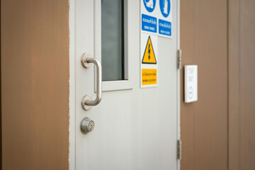 Close-up at handle of the thicked metal door of switchgear control room at the factory. Industrial equipment object photo, selective focus.