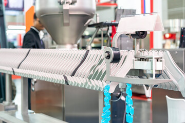 Close up sample imitate sausage stuffer put in collagen casings during hanging on hanger of automatic line conveyor machine holder for transport in manufacturing process food industrial