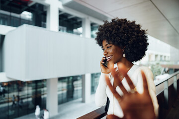 Portrait of happy african young woman talking on cellphone in city