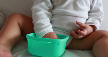 Baby eating blueberries sitting on sofa. Infant one year old toddler eats healthy snack